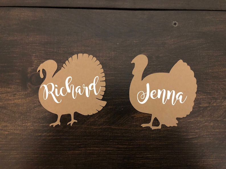 Puede incluir: Dos tarjetas de lugar de pavo de papel marr&oacute;n con los nombres "Richard" y "Jenna" escritos en blanco.