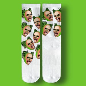 May include: White socks with a repeating pattern of a green-haired, orange-skinned face with a protruding tongue. The face has black eye makeup and a sinister expression. A quirky and unique accessory.