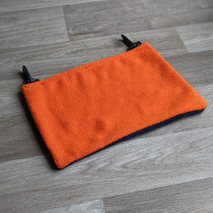 May include: Orange fleece neck warmer with a black trim and two black clips.