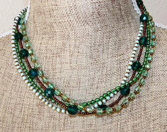 Collier lin et 4 rangées de rocailles, perles de métal et verre dans des tons verts et bronze.