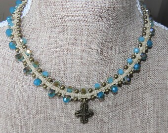 Collier "Mystique" en macramé de lin, perles bronzes et irisées "bleu d'eau" et pendentif croix couleur bronze