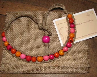 Collier court en graines d'açaï dans les tons rouge, orange et rose tissées dans la ficelle de lin lin