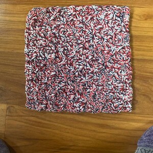 May include: A red, white, and blue knitted dishcloth. The dishcloth is made with a textured pattern.