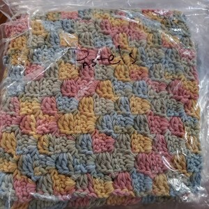 May include: A crocheted blanket with a square pattern in pastel colors of pink, blue, yellow, and green. The blanket is packaged in a clear plastic bag and has the word "Pastels" written on it.