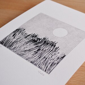 May include: A square black and white linocut print on white paper featuring a field of tall grass under a circular sun. The print includes the handwritten text 'Pf 21' on the left and '1/100' on the bottom, indicating a limited edition artwork.