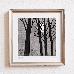 May include: A black and white print of a moonlit forest scene with five trees and a crescent moon. The print is framed in a light wood frame and has the text "PK 3" and "1/100" in the bottom corners.