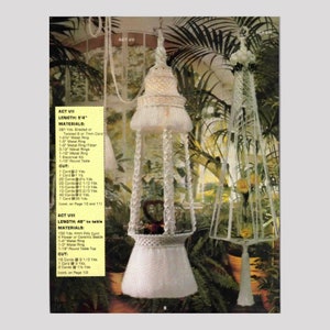 Peut inclure: Deux suspensions pour plantes en macramé sont présentées sur un fond de verdure. La première, de forme cloche blanche, est suspendue. La seconde, une structure haute et élancée, présente une forme conique. L'image comprend du texte.