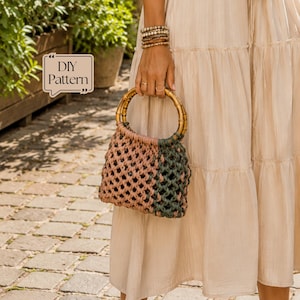 Könnte beinhalten: Eine Makramee-Handtasche mit geknotetem Design in Altrosa und Dunkelgrün, ausgestattet mit zwei runden Bambusgriffen. Die Tasche zeigt in der oberen linken Ecke ein Textfeld mit den Worten DIY Pattern. Die Konstruktion besteht aus geflochtener Kordel.