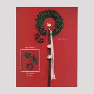 May include: A green crocheted wreath with a red bow and a white Santa figure hanging from it. There are two smaller green crocheted ornaments, one shaped like a wreath and the other like a holly sprig, with red berries. The text "Santa's Wreath" is printed below the wreath.