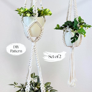 Può includere: Due portavasi in macramè, ciascuno con un vaso in ceramica bianco pieno di piante verdi. I portavasi in corda bianco sporco presentano un motivo intrecciato. Il testo "DIY Pattern" e "Set of 2" è visibile.