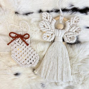 Macramé Christmas ornaments — a tasselled angel and a small crochet-style stocking with a suede bow — displayed on soft fur