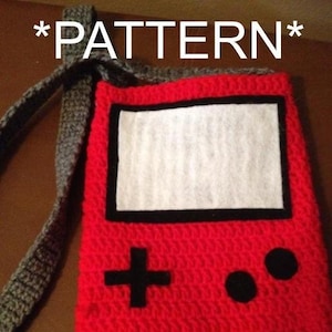 May include: Red crocheted bag with a black and white screen and buttons, resembling a handheld video game console. The bag has a gray crocheted strap. The text *PATTERN* appears above and below the bag.
