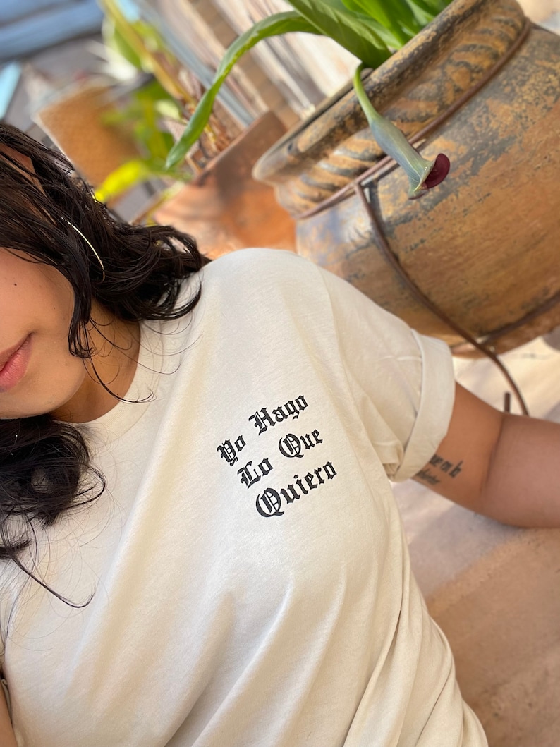 May include: A white t-shirt with black text that reads "Yo Hago Lo Que Quiero".