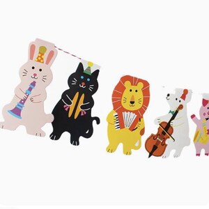 以下が含まれることがあります： 音楽の楽器を演奏する動物のキャラクターが5人いるカラフルなガーランド。ピンクのウサギはトランペットを演奏し、黒い猫はシロフォンを演奏し、黄色のライオンはアコーディオンを演奏し、白いクマはチェロを演奏し、ピンクのブタはサックスを演奏しています。