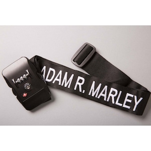 May include: Black luggage strap with a combination lock and the text "ADAM R. MARLEY" printed in white.