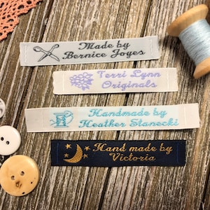 May include: Four white fabric labels with different embroidery designs and text. The labels read "Made by Bernice Joyes", "Terri Lynn Originals", "Handmade by Heather Stonecki", and "Hand made by Victoria".