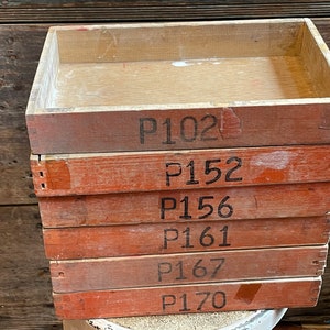 May include: Stack of six wooden boxes with labels reading "P102", "P152", "P156", "P161", "P167", and "P170".