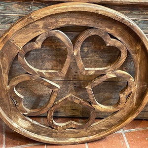 May include: A round wooden wall decor with a carved design of five overlapping hearts. The wood is a dark brown color and has a rustic finish.