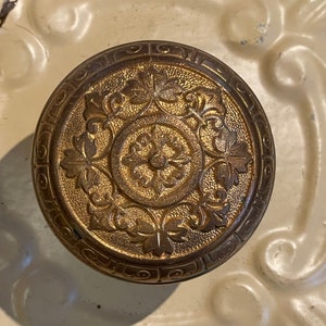 May include: A gold-toned door knob with an intricate floral design.