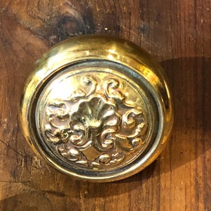 May include: A gold-toned door knob with a decorative floral design.