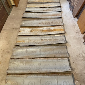 May include: A set of ten antique tin ceiling tiles with a decorative embossed pattern. The tiles are in various shades of gray and brown, with some rust and wear.