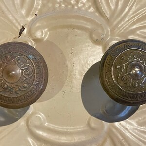 May include: Two antique brass door knobs with intricate floral designs.