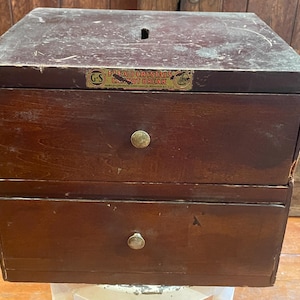 May include: A wooden box with two drawers. The box has a label that reads "Flexo Crayons G-S Crayon Brick".