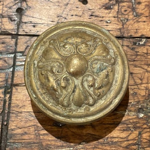 May include: A brass door knob with an ornate design featuring four stylized floral motifs.