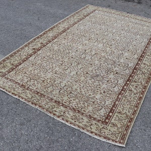 Könnte beinhalten: Ein cremefarbener Teppich mit braunem Blumenmuster und einem Rand. Der Teppich hat einen Fransenrand.