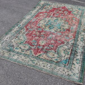 Könnte beinhalten: Ein Vintage-Teppich mit einem verblassten Rot-, Türkis- und Cremefarbton. Der Teppich hat ein traditionelles persisches Design mit komplizierten Blumenmustern.