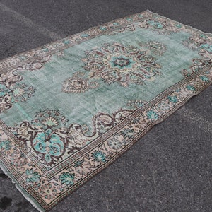 Könnte beinhalten: Ein Vintage-Teppich in Teal und Creme mit einem floralen Muster. Der Teppich hat einen abgenutzten Look und ist aus Wolle.