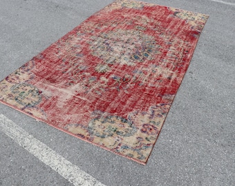 Op de afbeelding: Een vintage rood en beige tapijt met een vervaagd bloemenpatroon. Het tapijt heeft een verweerde uitstraling en is perfect om elke kamer een vleugje bohemian stijl te geven.
