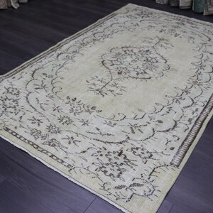 Könnte beinhalten: Ein vintage cremefarbener Teppich mit braunem Blumenmuster. Der Teppich hat einen abgenutzten Look und einen dezenten Glanz.