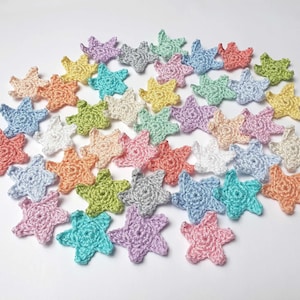 Könnte beinhalten: Eine Sammlung von gehäkelten Sternen in verschiedenen Pastellfarben, darunter Rosa, Blau, Grün, Gelb und Weiß.