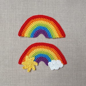 May include: Two crocheted rainbow appliques. One rainbow is a complete arch in red, orange, yellow, green, blue, and purple. The second rainbow has a yellow sun and a white cloud attached.