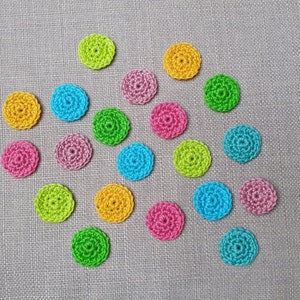 Può includere: Assortimento di cerchi all'uncinetto colorati in varie tonalità di verde, blu, rosa, giallo e viola. I cerchi sono disposti in uno schema casuale su uno sfondo testurizzato grigio chiaro.