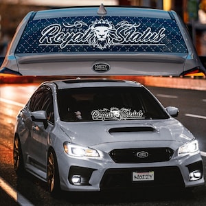 May include: A white Subaru WRX with a black and white "Royal Status" decal on the windshield. The decal features a lion with a crown and the text "Royal Status" in a stylized font.