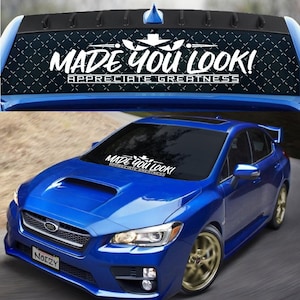 May include: A blue Subaru WRX with a white windshield banner that reads "MADE YOU LOOK! APPRECIATE GREATNESS".