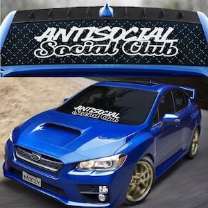 May include: A blue Subaru WRX with a black windshield sunshade featuring the white text "Antisocial Social Club".