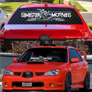 May include: A red Subaru Impreza WRX with a black and white "Sinister Motives" windshield banner. The banner features a skull and crossbones graphic and the text "Sinister Motives" in a bold, white font. The car has a black rear spoiler and a black front bumper with a black grille. The car has yellow fog lights and a black license plate that reads "Noizy".