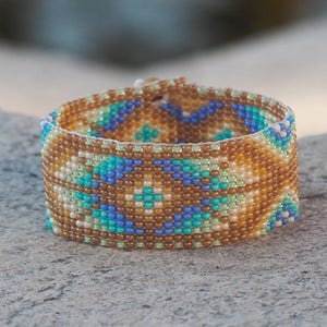 Könnte beinhalten: Ein Armband aus Perlen mit einem geometrischen Muster in Braun-, Blau- und Grüntönen.