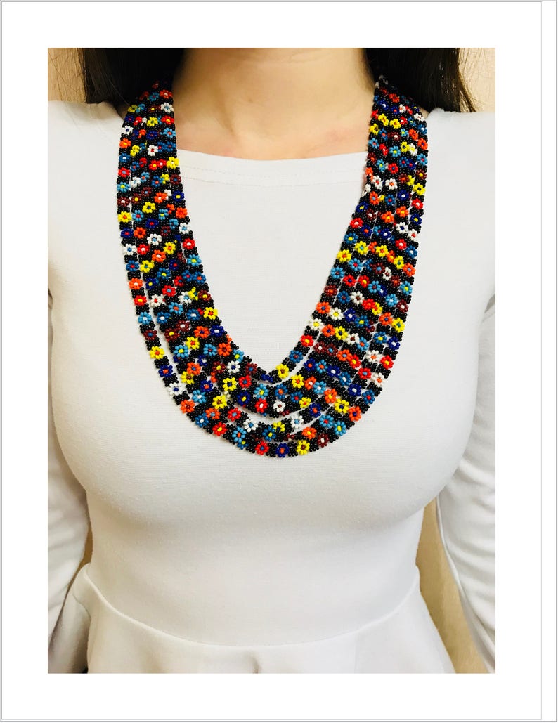 May include: Multi-strand beaded necklace with a floral pattern in shades of red, orange, yellow, blue, white, and black.