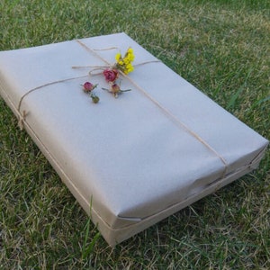 May include: A brown paper package tied with twine and decorated with dried flowers. The flowers are yellow, pink, and white.