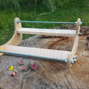 May include: A wooden frame with two adjustable bars and a piece of twine. The frame is used for pressing flowers.