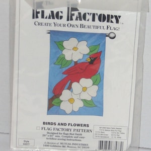 Könnte beinhalten: Ein Flag Factory-Muster für eine Flagge von 71 cm x 124 cm mit einem Kardinal und weißen Blumen auf blauem Hintergrund. Das Muster trägt den Titel "Birds and Flowers" und enthält Anweisungen zum Nähen der Flagge. Das Muster ist eine Abteilung von Mutual Industries, 1400 Goldmine Rd., Monroe, NC 28110.