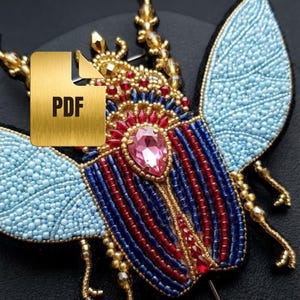 May include: A detailed, beaded insect brooch with a central pink gemstone and accents of red, blue, and gold. The wings are light blue, and the body features intricate beadwork. A gold PDF icon is in the image.