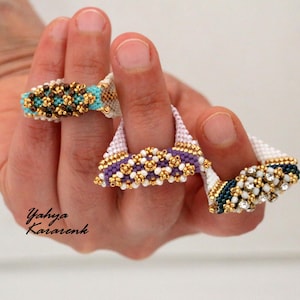 May include: Three beaded rings featuring intricate woven patterns. One ring has turquoise and brown beads, another has purple and white beads with gold accents, and the third features dark blue, white, and clear crystal beads on a white base.