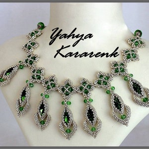 以下が含まれることがあります： 銀色と緑色のビーズでできたネックレスで、涙の形をしています。ネックレスの中央には、涙の形をしたペンダントが5つ付いています。ネックレスには「Yahya Kararenk」の署名があります。