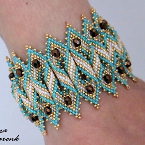 Peut inclure: Un bracelet de perles avec un motif géométrique. Le bracelet est composé de perles turquoise, dorées, blanches et marron. Le bracelet mesure environ 3,8 cm de large.