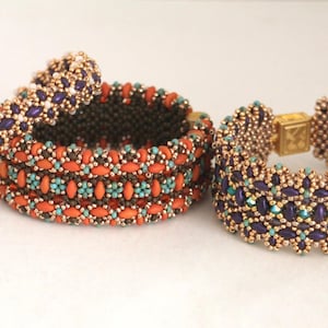 May include: Three beaded bracelets in different colors and patterns. The bracelets are made with small, colorful beads and have a gold-toned finish. The bracelets are stacked on top of each other.